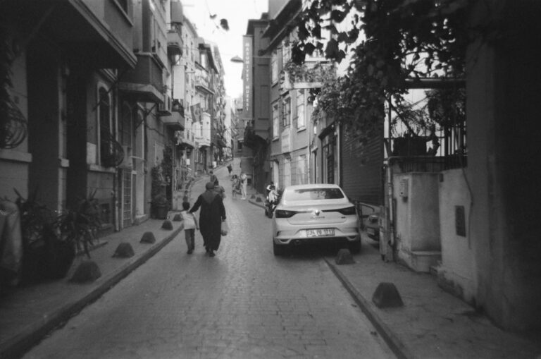 grayscale photo of man walking on sidewalk