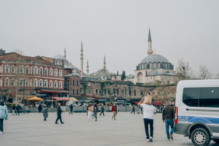 a group of people walking in a plaza with buildings in the background