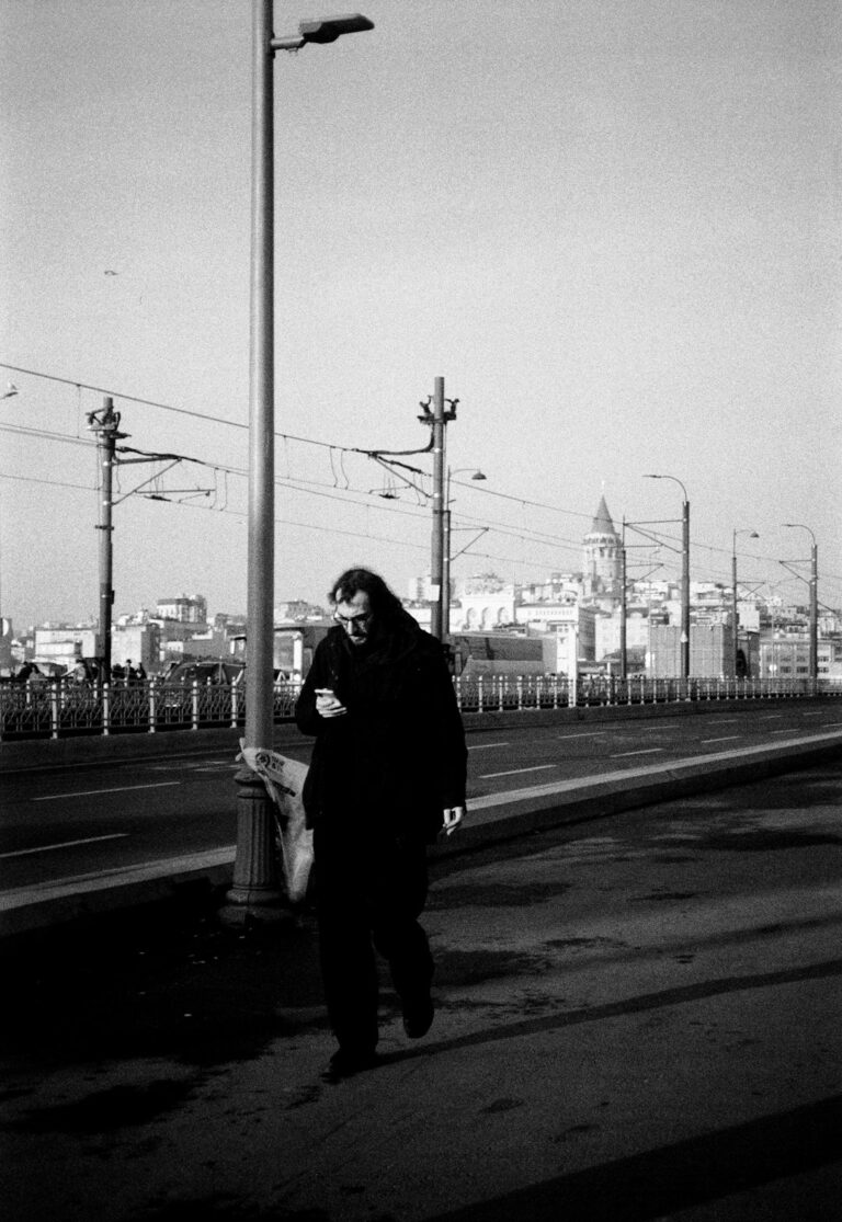 A woman walking down a street next to a street light